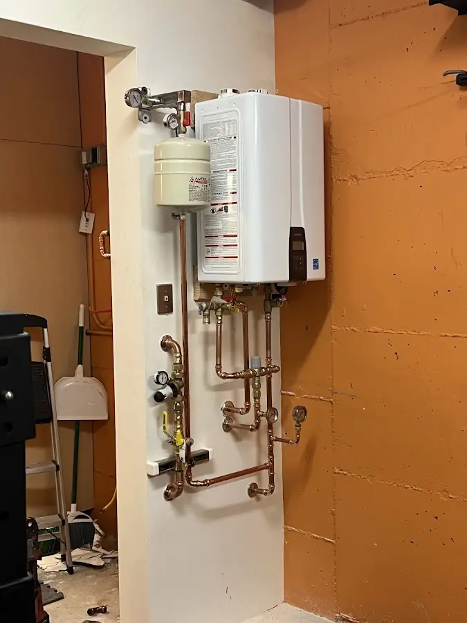 Plumbing technician inspecting water heater connections in Leominster